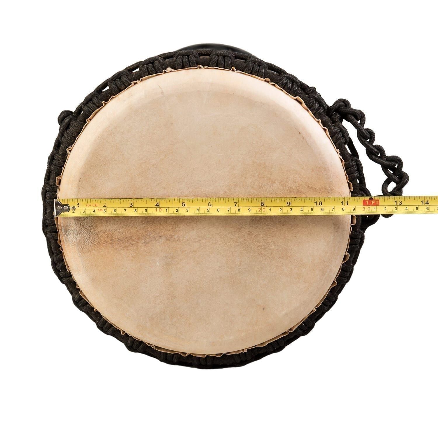 Top-down view of a djembe drum with a goatskin head and black rope tuning. A measuring tape indicates the diameter of the drumhead - Natural Wide Top 8 inch diameter, 30cm high.