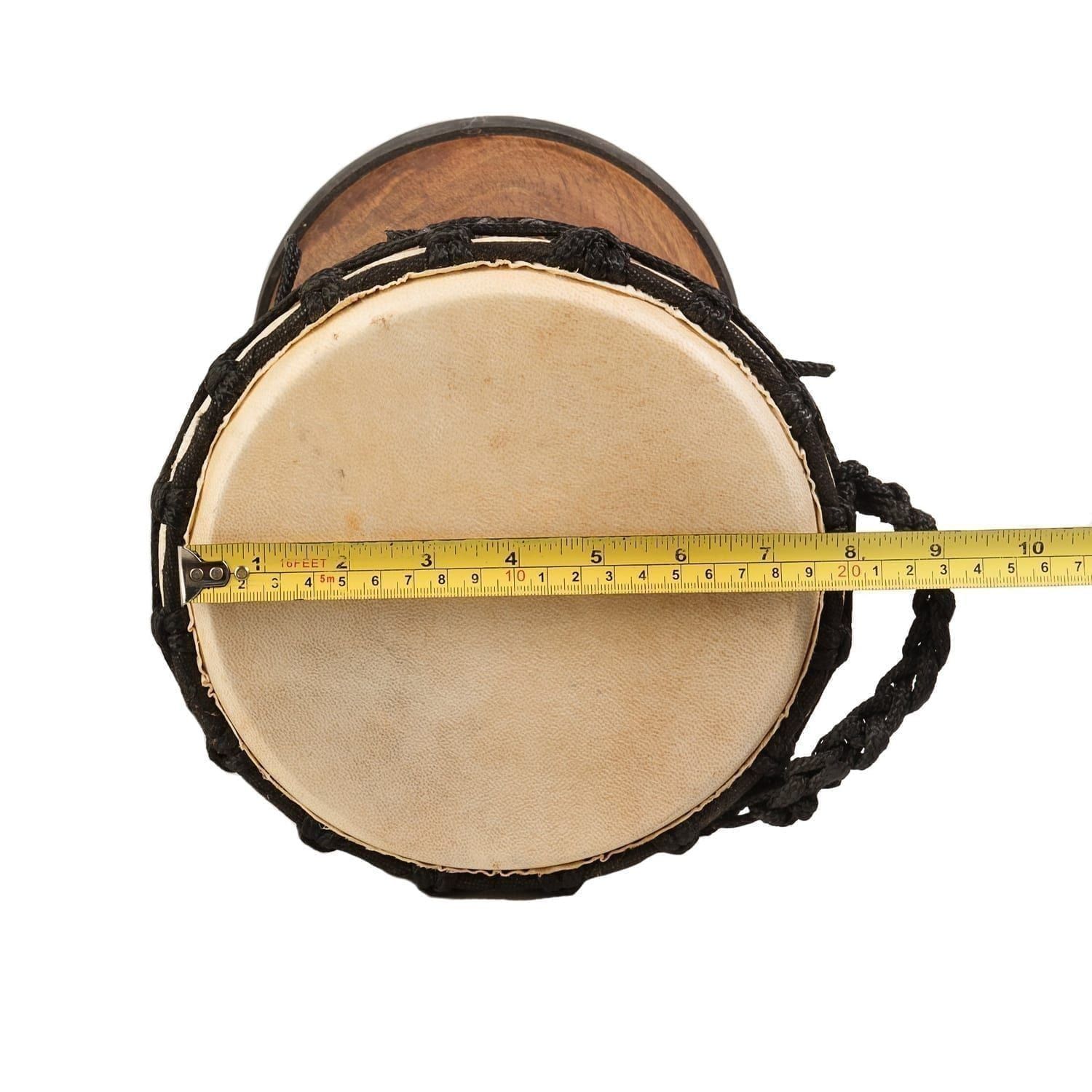 Top-down view of a djembe drum with a goatskin head and black rope tuning. A measuring tape indicates the diameter of the drumhead - Natural Wide Top 8 inch diameter, 30cm high