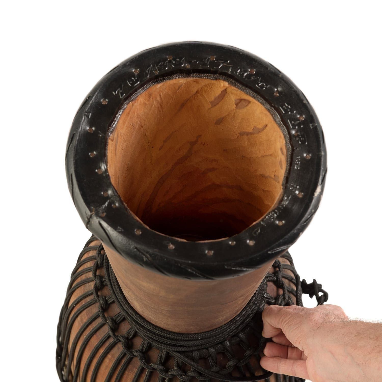 Top view of a djembe drum showcasing its hollow wooden interior, intricately carved black rim, inside of the drum shell, and traditional rope tuning system.