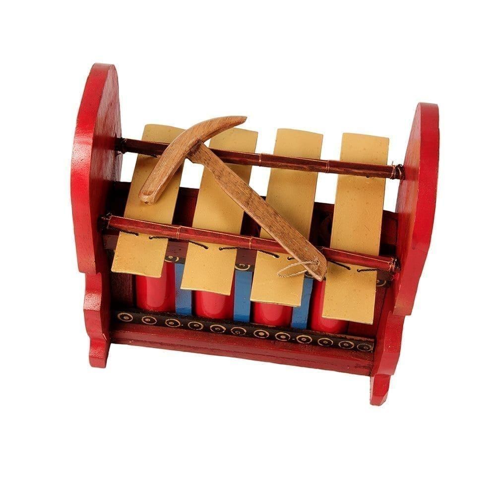 This is a product image of the Gamelan - Budget - Large 4 key. The instrument has four gold keys suspended by bamboo and wire. The casing is mainly red with some blue, gold and black decoration. A beater is laying on top of the instrument. The image has been taken from above and in front, with the instrument facing slightly to the left.