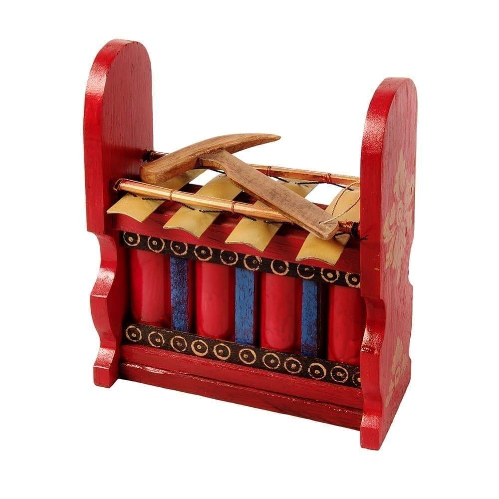 This is a product image of the Gamelan - Budget - Medium 4 key. The instrument has four gold keys suspended by bamboo and wire. The casing is mainly red with some blue, gold and black decoration. A beater is laying on top of the instrument. The image has been taken from the front and the instrument is facing slightly to the left.