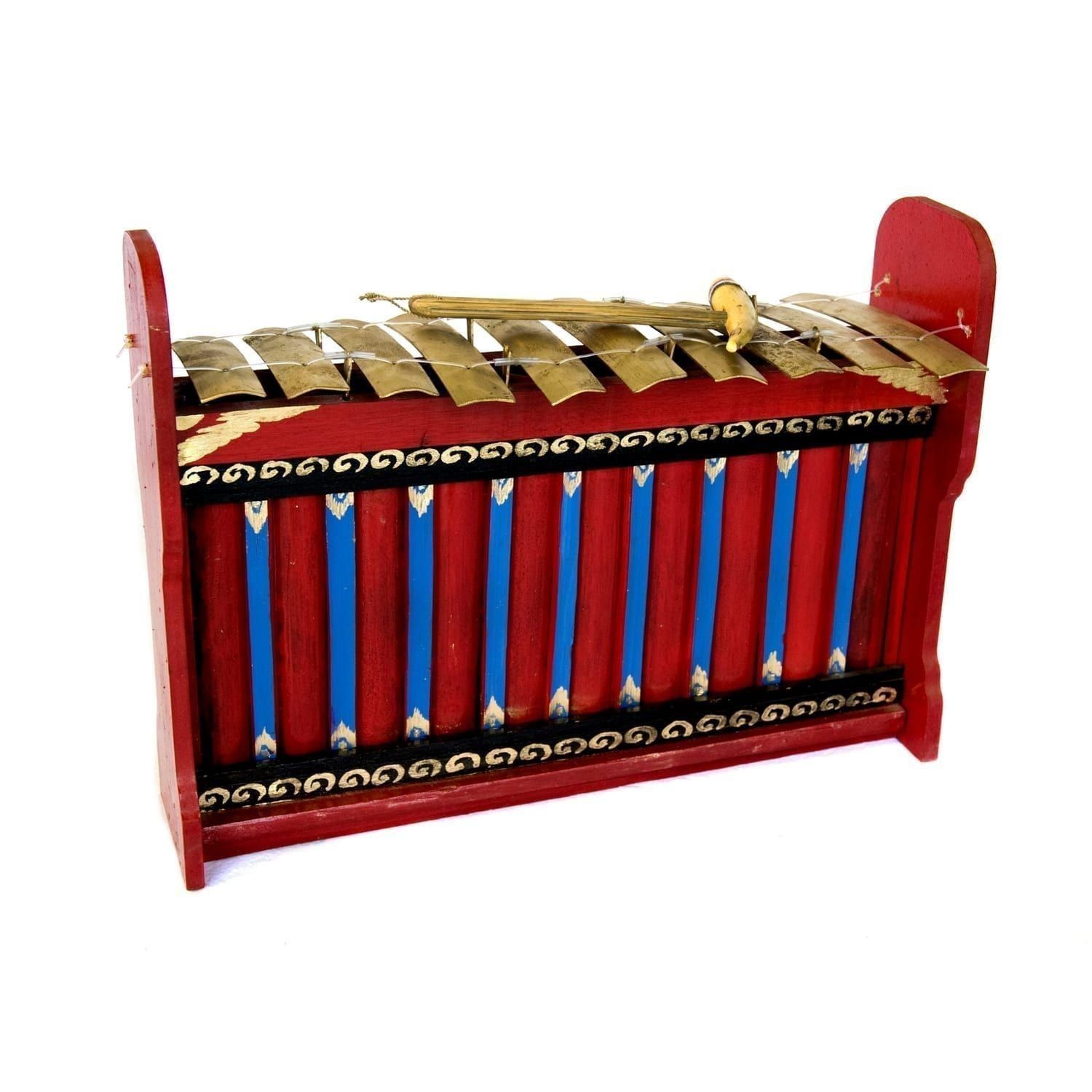 This is a product image of the Gamelan (Gangsa Kantilan) - Budget - Small 10 key. It is an angled shot with the front of the instrument facing to the right. It is red and blue with gold keys suspended by wire, and the beater is lying on top of the keys.