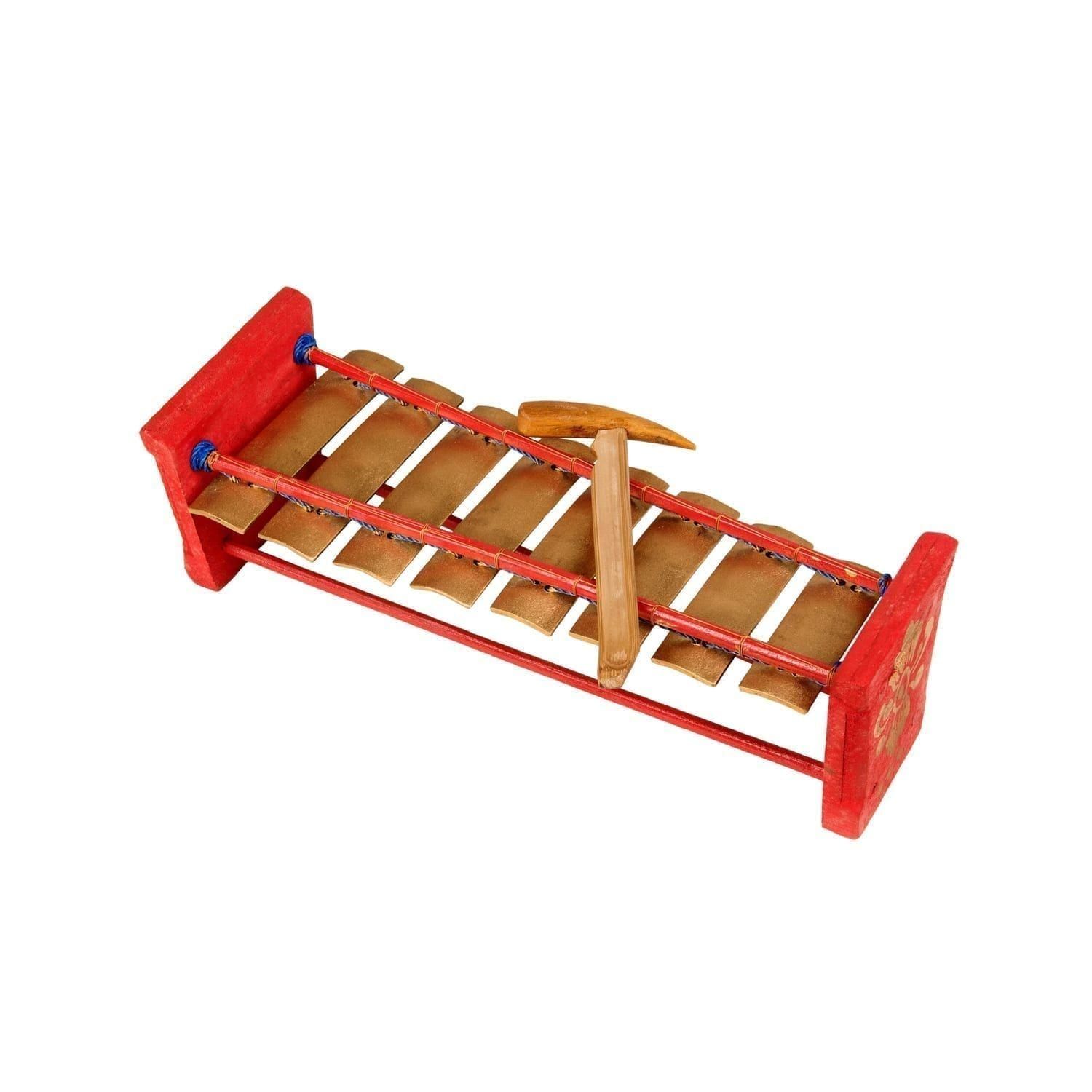 This is a product image of the Gamelan (Metallophone) - C major from a higher angle. It is largely red in colour with eight metal bars suspended across two bamboo struts.
