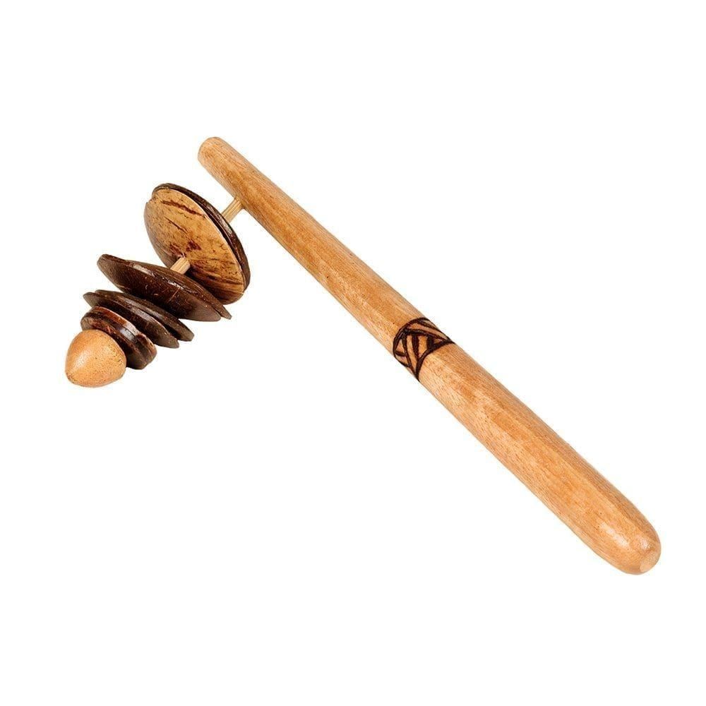 This is a product image of the Rackattack. It is a wooden handle with a line pattern burnt into it for decoration. At the top are some shells attached to a protruding section. The instrument is angled from the bottom left to the top right.