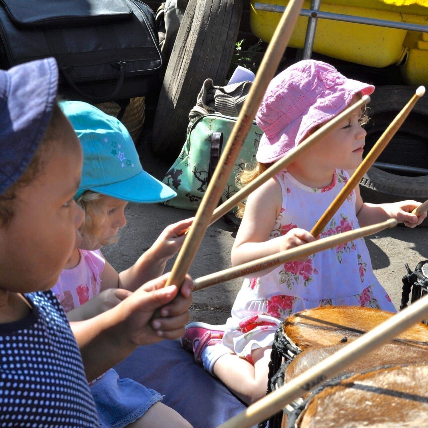 This is an action shot of three children playing Drums for Schools' Dundun Bamboo