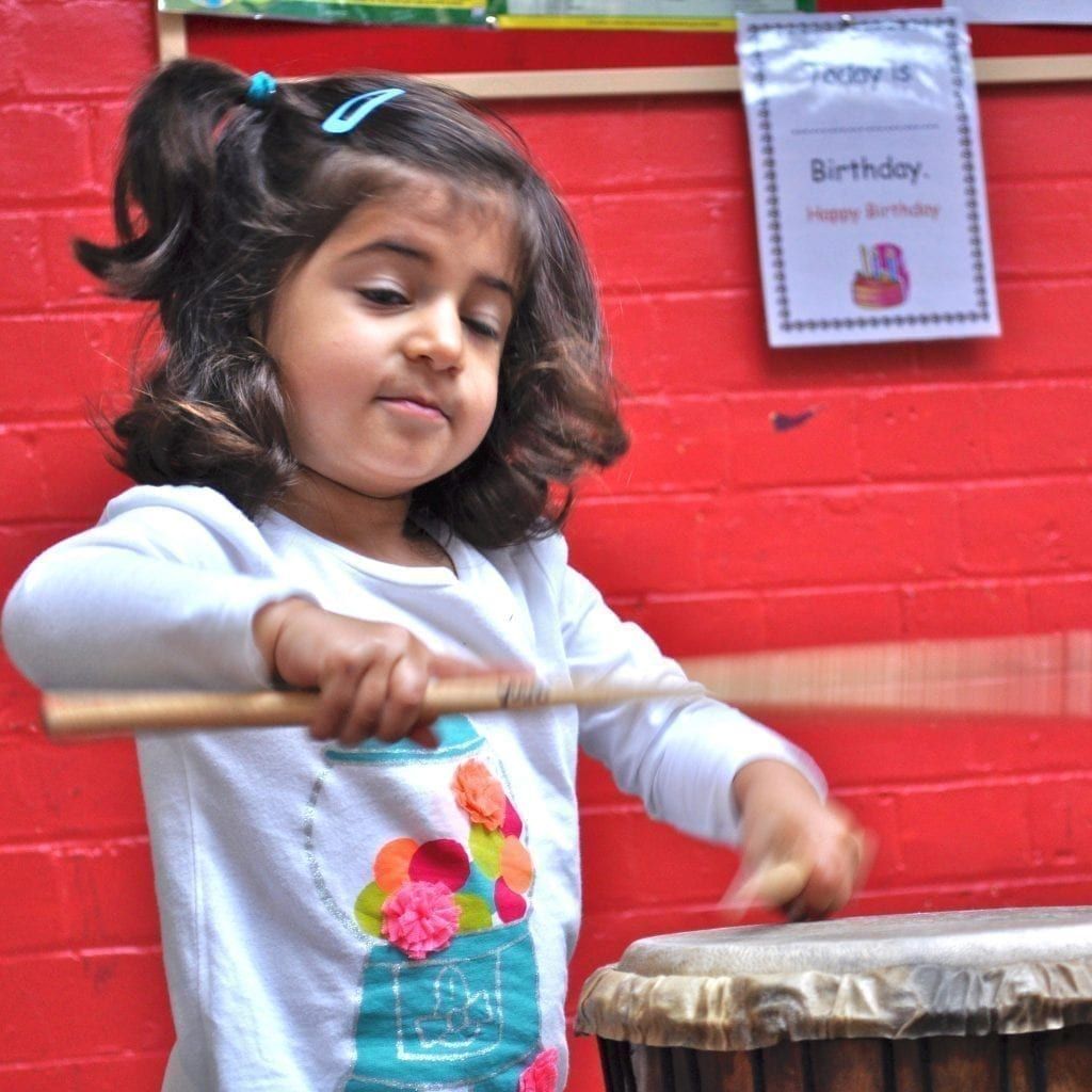 Early Years child playing Drums for Schools' Djembe Drum