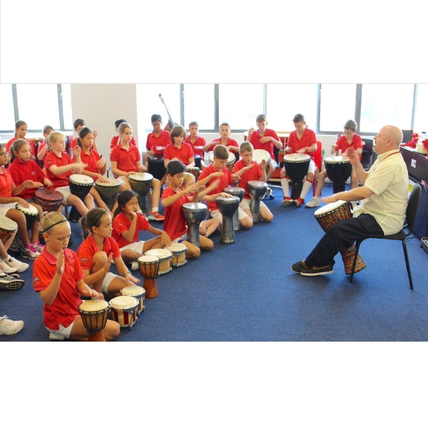 West African drumming djembe workshop with a group of children playing Djembe drums under the guidance of Andy Gleadhilll, Hong Kong, emphasizing cultural education and rhythmic collaboration.