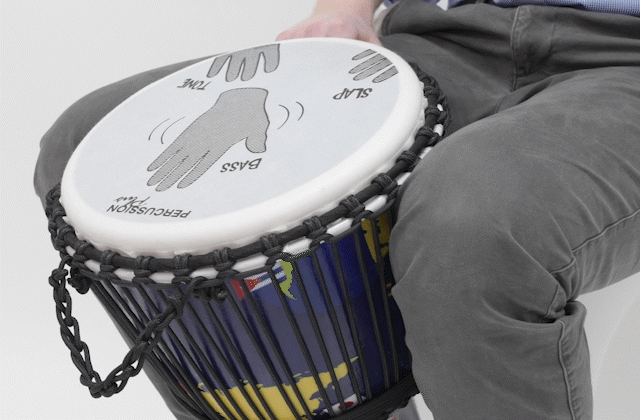 Close-up of hands demonstrating slap technique on a Slap Djembe drum, showcasing labeled positions for accurate drumming.