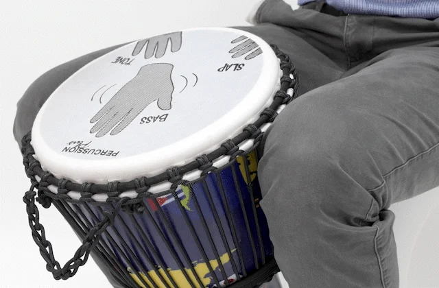 Person playing a Slap Djembe drum with labeled hand positions for slap, bass, and tone techniques, emphasizing educational drumming guidance.